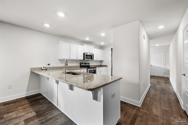 kitchen featuring kitchen peninsula, a breakfast bar area, stainless steel appliances, white cabinets, and sink