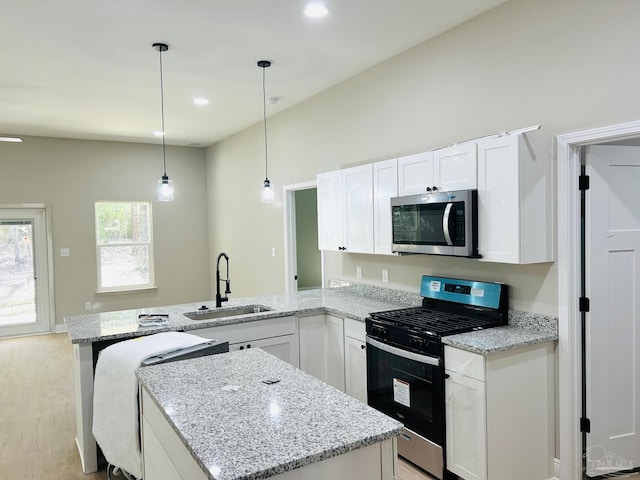 kitchen with light stone counters, a peninsula, stainless steel appliances, white cabinetry, and a sink