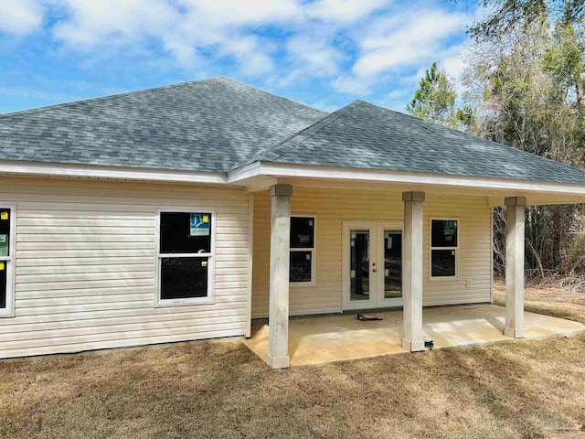 rear view of property featuring french doors, roof with shingles, and a patio