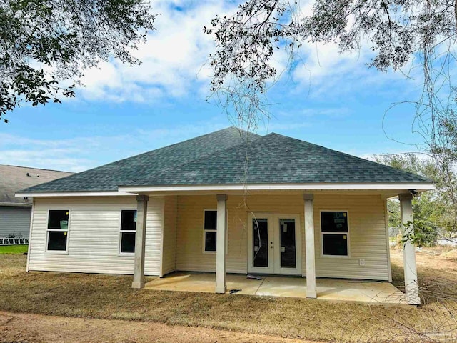 rear view of house with french doors, a lawn, a patio area, and a shingled roof