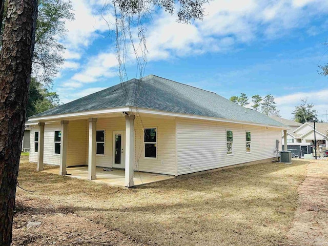 rear view of property featuring roof with shingles, central AC, and a patio