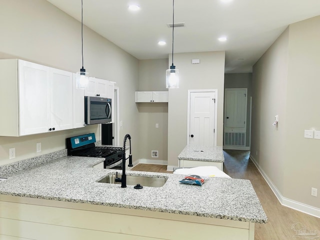 kitchen featuring stainless steel appliances, a sink, a kitchen island, light stone countertops, and a peninsula