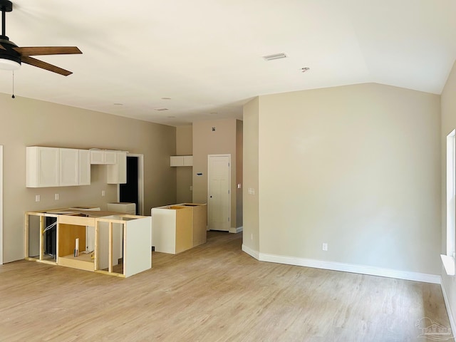 kitchen with baseboards, white cabinetry, vaulted ceiling, and light wood finished floors