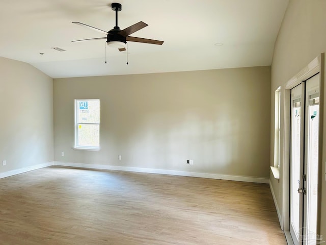 spare room featuring visible vents, baseboards, a ceiling fan, vaulted ceiling, and light wood-type flooring