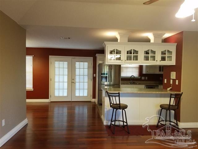 kitchen with white cabinetry, sink, stainless steel refrigerator with ice dispenser, kitchen peninsula, and a breakfast bar area