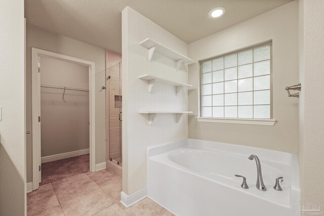 full bath featuring a spacious closet, a stall shower, a bath, and baseboards
