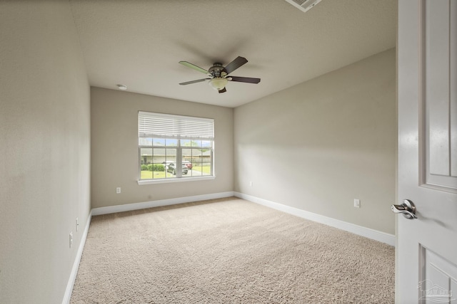 carpeted spare room with a ceiling fan and baseboards