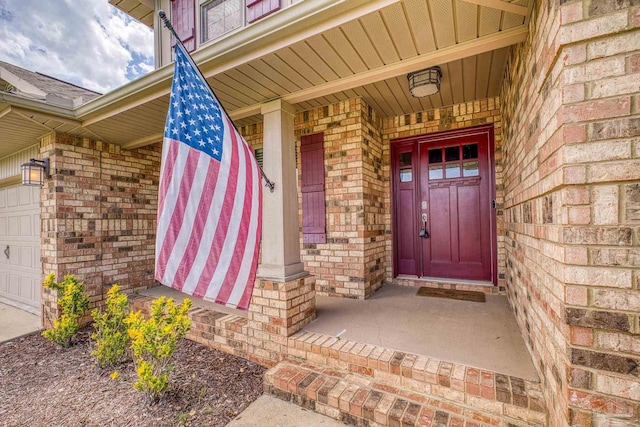 doorway to property featuring covered porch and brick siding