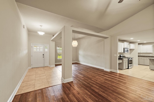 foyer featuring light wood-type flooring, baseboards, lofted ceiling, and recessed lighting