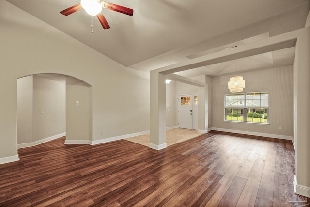 unfurnished room featuring wood-type flooring, a ceiling fan, arched walkways, and baseboards