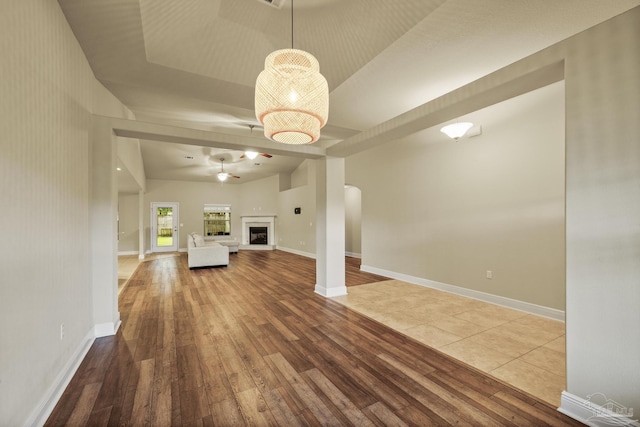 unfurnished living room with hardwood / wood-style floors, baseboards, and arched walkways
