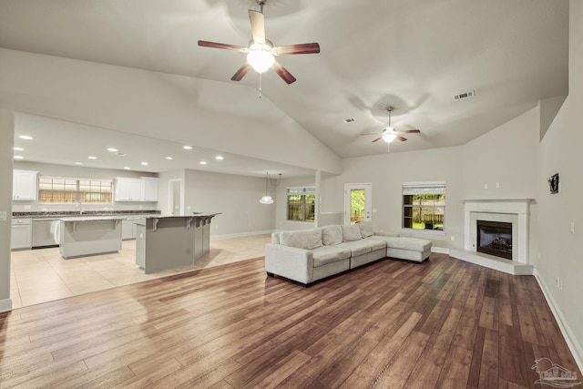 living room featuring a ceiling fan, light wood finished floors, plenty of natural light, high vaulted ceiling, and recessed lighting