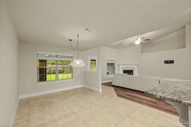 unfurnished living room with light tile patterned floors, ceiling fan, baseboards, a fireplace, and lofted ceiling