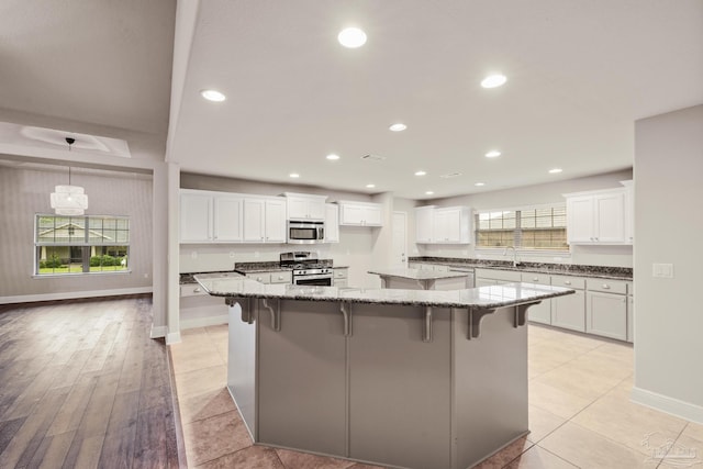 kitchen featuring stainless steel appliances, a sink, white cabinetry, a large island, and recessed lighting
