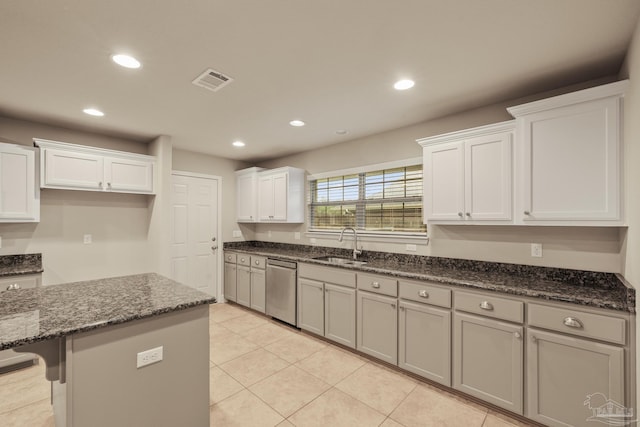 kitchen with stainless steel dishwasher, a sink, recessed lighting, white cabinets, and dark stone countertops