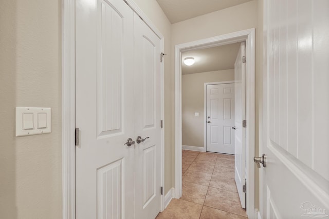 corridor with light tile patterned floors and baseboards