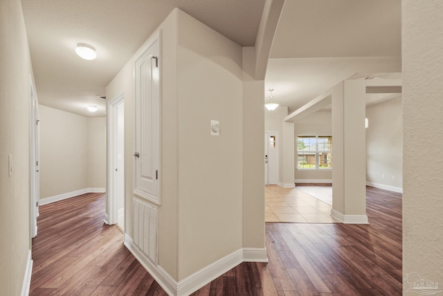 corridor with dark wood-style floors and baseboards