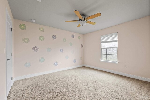 spare room featuring carpet floors, baseboards, ceiling fan, a smoke detector, and wallpapered walls