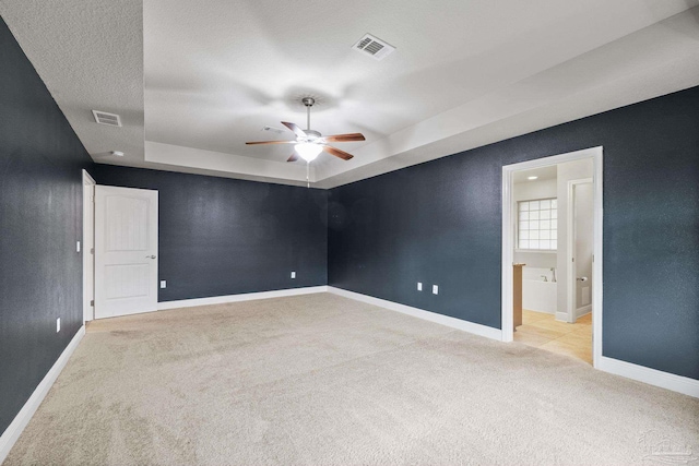 carpeted spare room with a tray ceiling, ceiling fan, and baseboards