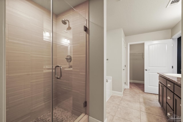 full bath featuring a stall shower, tile patterned floors, vanity, a spacious closet, and a garden tub