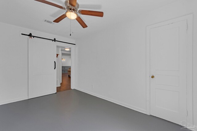 407 Rue Max St, Pensacola, FL 32507 - unfurnished bedroom with a barn door, concrete floors, baseboards, and ceiling fan