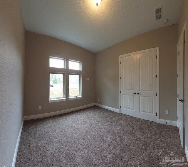 unfurnished bedroom with carpet flooring, a closet, baseboards, and visible vents