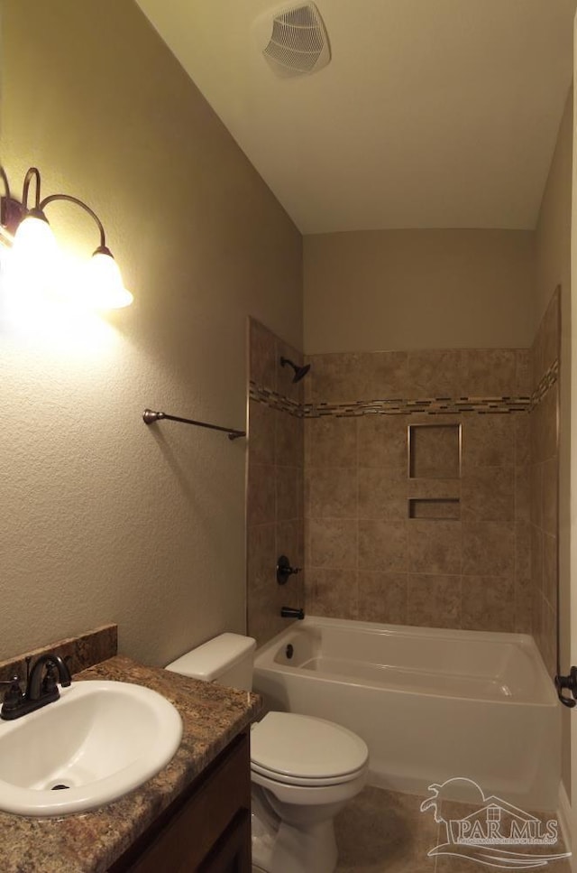 bathroom featuring visible vents, toilet, vanity, a textured wall, and shower / tub combination
