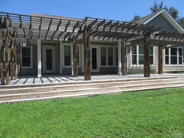 rear view of property featuring a lawn, a pergola, and a deck