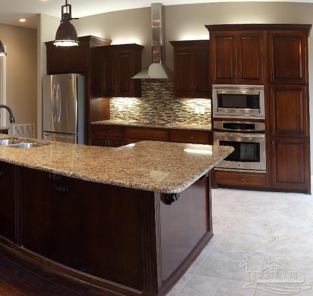 kitchen with stainless steel appliances, wall chimney exhaust hood, tasteful backsplash, sink, and pendant lighting