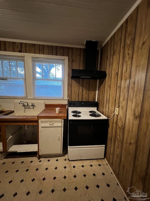 kitchen featuring range with electric cooktop, wall chimney exhaust hood, crown molding, and wood walls