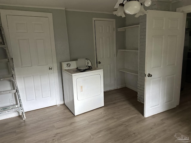 clothes washing area featuring washer / dryer, ornamental molding, and light hardwood / wood-style floors