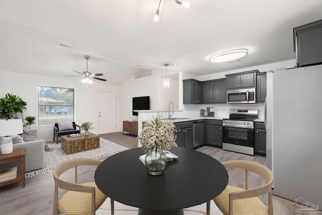 dining space with sink, ceiling fan, lofted ceiling, and light hardwood / wood-style floors