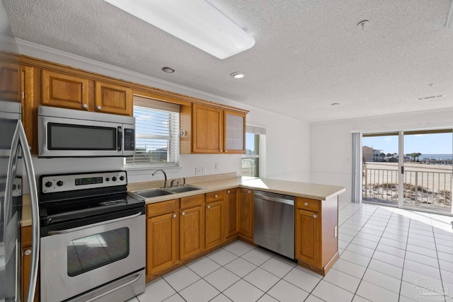 kitchen with kitchen peninsula, a textured ceiling, sink, ornamental molding, and appliances with stainless steel finishes