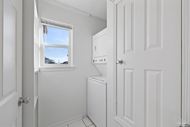 washroom with stacked washer / drying machine, a textured ceiling, and light tile patterned floors