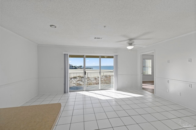 tiled empty room featuring crown molding, a view of the beach, a textured ceiling, a water view, and ceiling fan