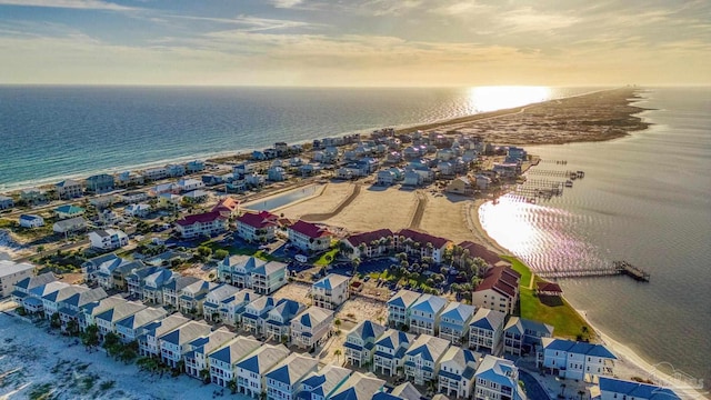 aerial view at dusk featuring a water view and a view of the beach