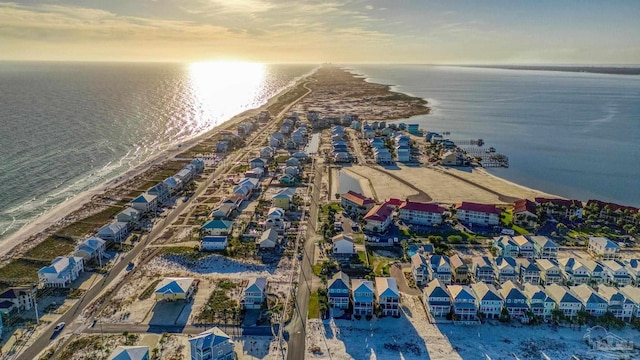 aerial view at dusk with a water view and a view of the beach