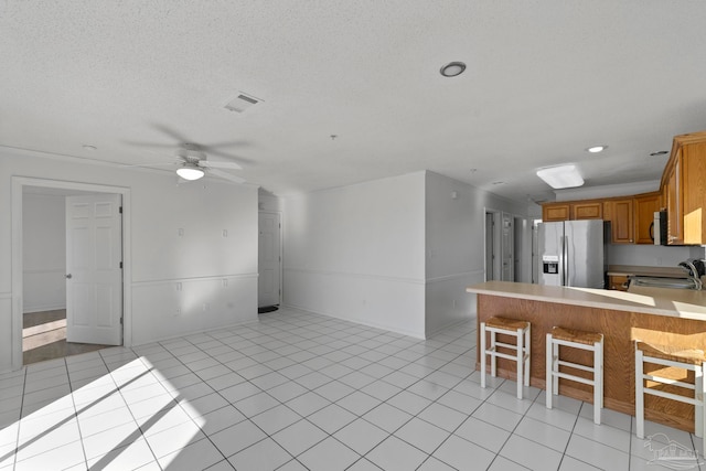 kitchen with appliances with stainless steel finishes, a kitchen bar, light tile patterned floors, sink, and kitchen peninsula