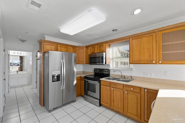 kitchen with ornamental molding, appliances with stainless steel finishes, a textured ceiling, light tile patterned floors, and sink