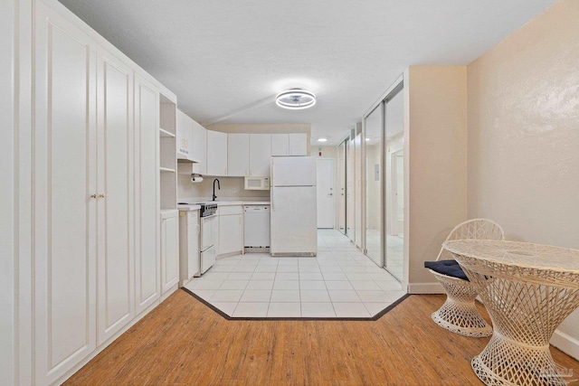 kitchen featuring sink, light hardwood / wood-style flooring, white cabinetry, and white appliances