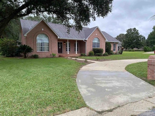 ranch-style home with brick siding, roof with shingles, and a front yard