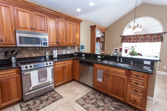 kitchen featuring a peninsula, appliances with stainless steel finishes, brown cabinets, and a sink