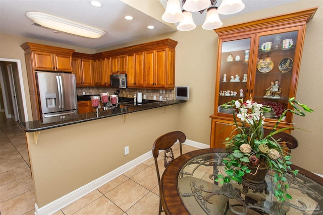 kitchen featuring stainless steel appliances, brown cabinets, glass insert cabinets, and a peninsula