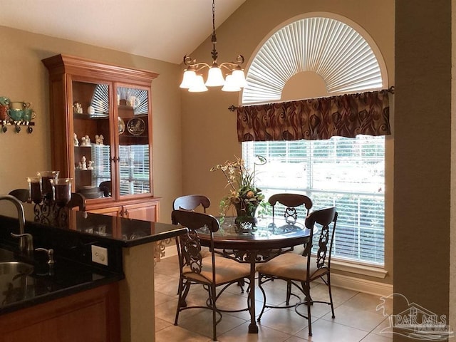 dining area featuring a chandelier, light tile patterned flooring, vaulted ceiling, and baseboards