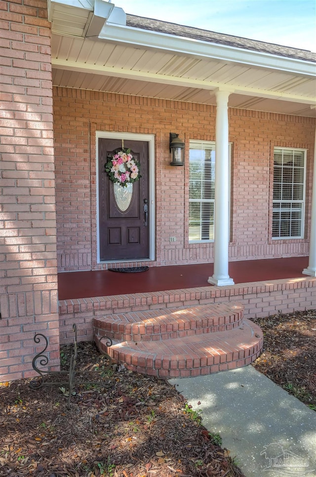 doorway to property featuring brick siding and a porch