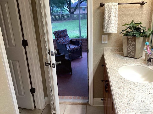 bathroom featuring tile patterned flooring, a textured wall, and vanity