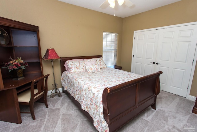 bedroom featuring a closet, light colored carpet, ceiling fan, and baseboards