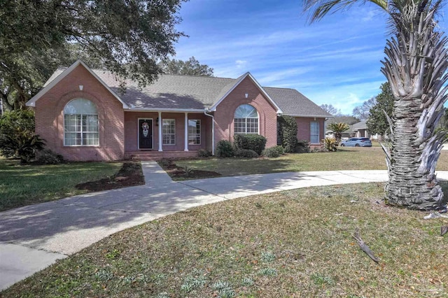 ranch-style house featuring a front yard, brick siding, and roof with shingles