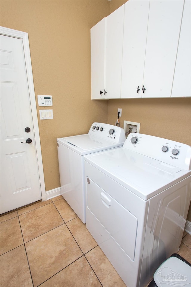 laundry area with washing machine and dryer, cabinet space, baseboards, and light tile patterned floors