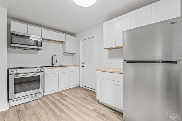 kitchen with white cabinetry, sink, light hardwood / wood-style flooring, and appliances with stainless steel finishes